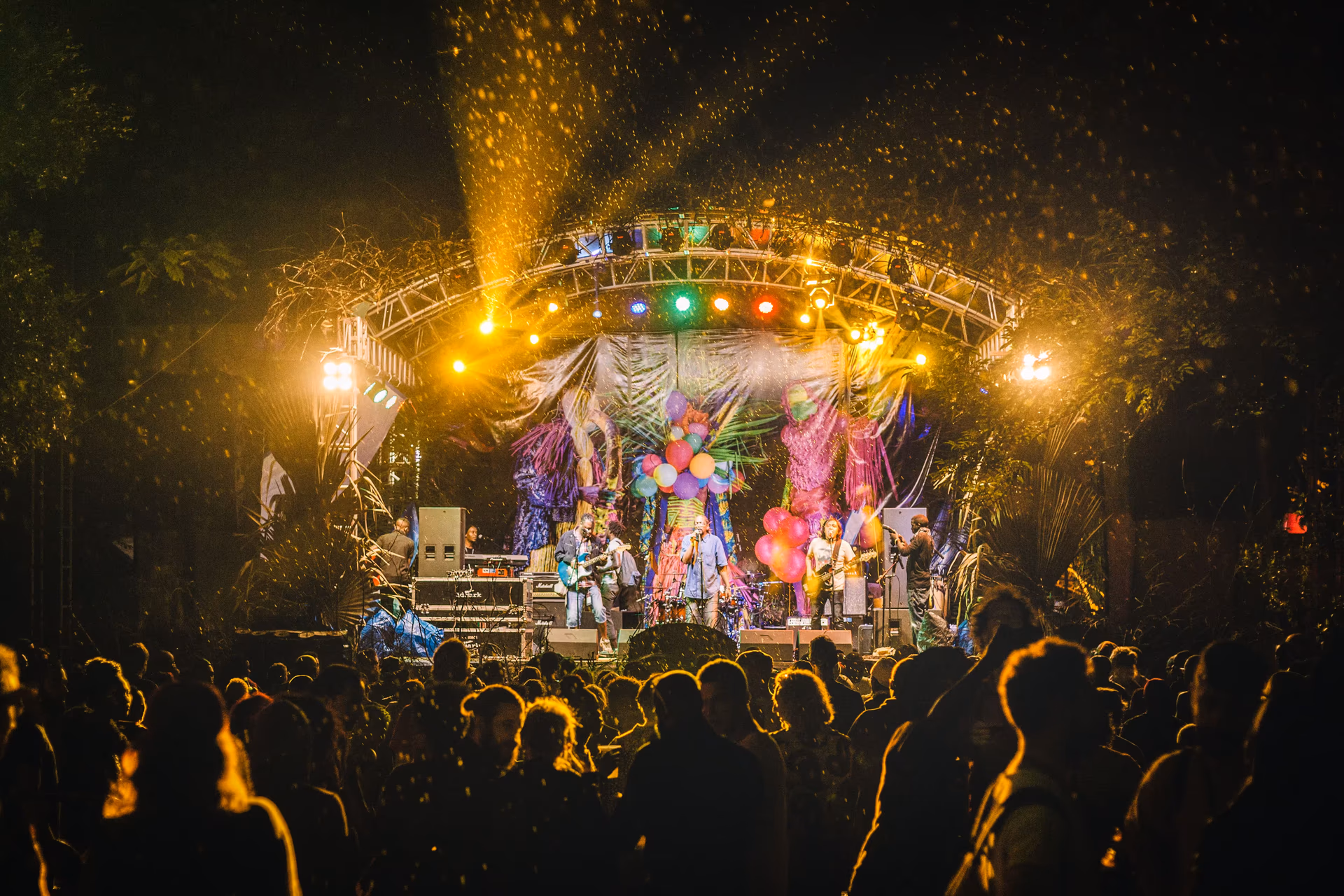 Massive crowd of festival-goers dancing at Nyege Nyege Festival with hands raised under colorful lights